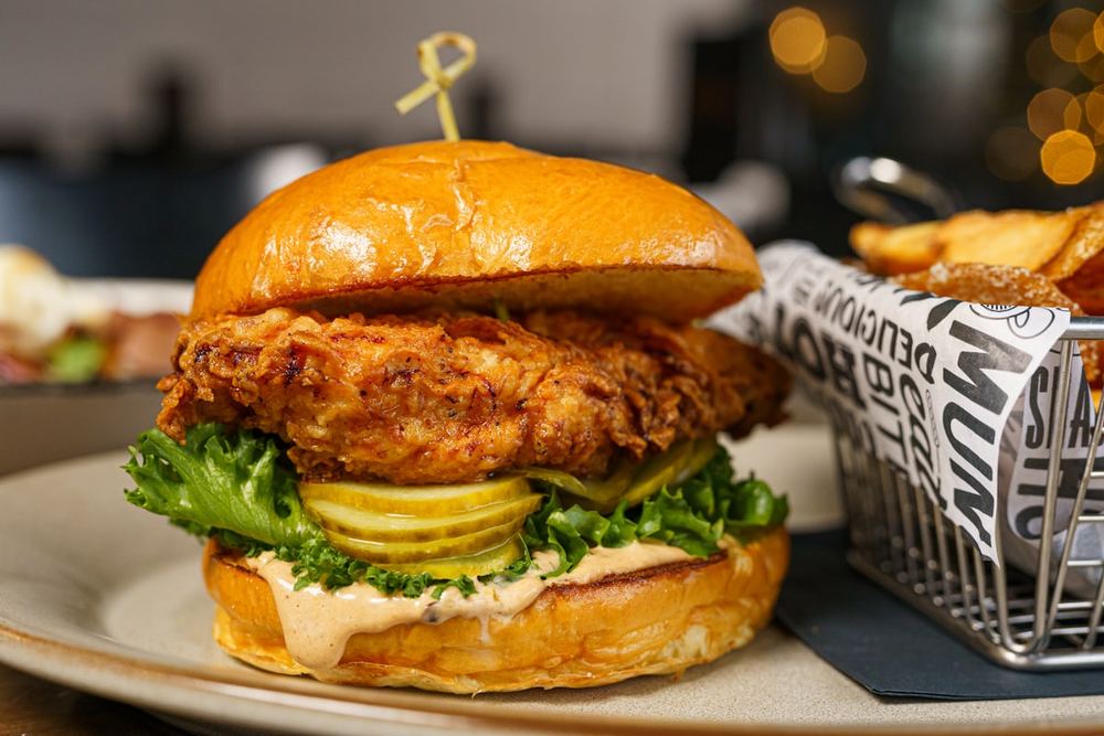 A crispy chicken burger served with a basket of hot chips