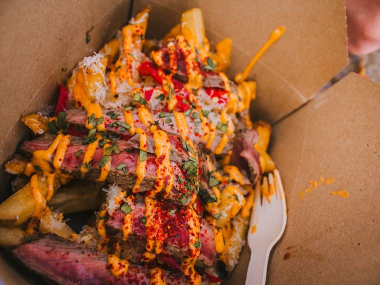 A snack box of fries loaded with meat and sauces